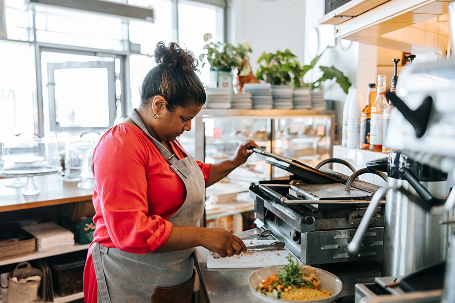 En kvinna som står och lagar mat i ett kök.