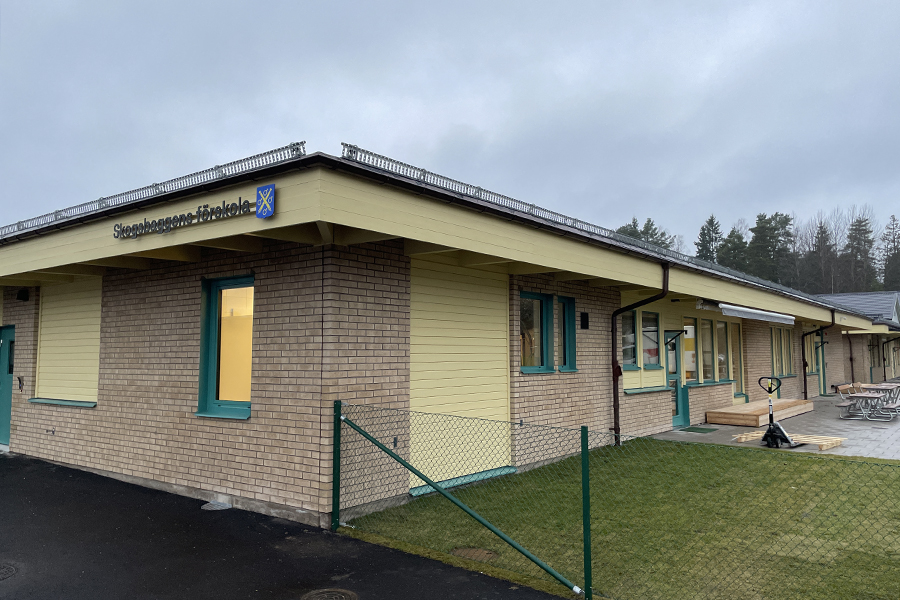 En byggnad med gult tegel och gröna fönsterkarmar.  