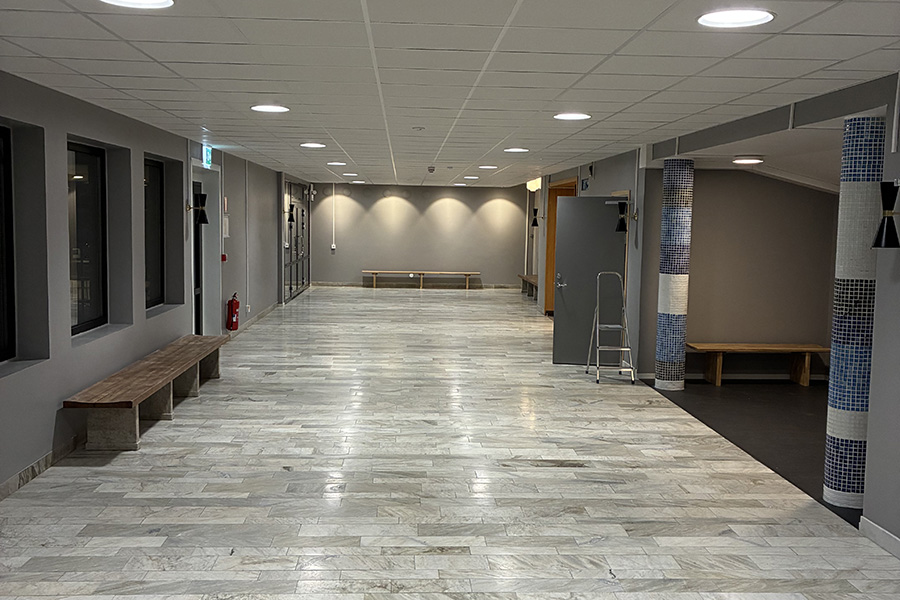 Ett stort rum med ljust golv. Längst den vänstra väggen står en träbänk.