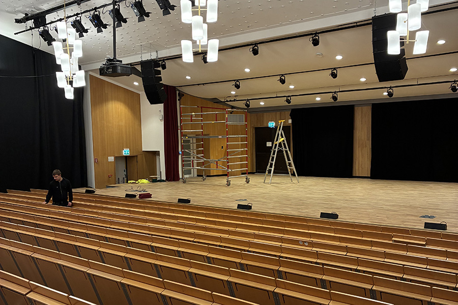 En scen med trägolv. Mitt på scenen står en stege .