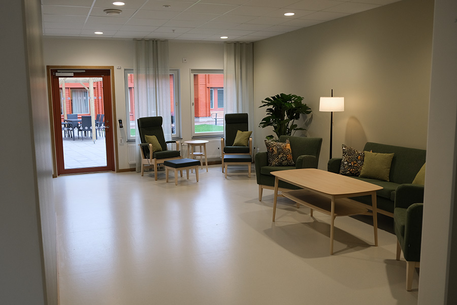 Ett rum med ljusa väggar och soffor och fåtöljer som står längs väggen.