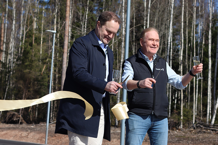 Två män håller i en varsin sax och klipper i ett band.