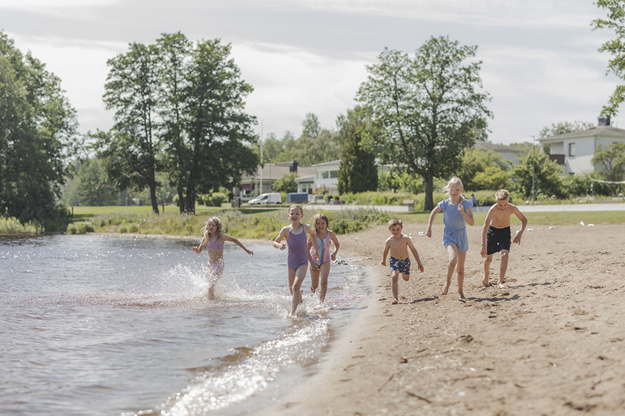 Barn springer längs strandkanten.