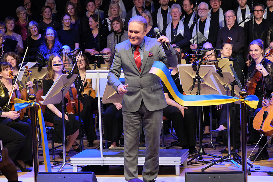 En man i grå kavaj klipper i ett blått och gult band. 