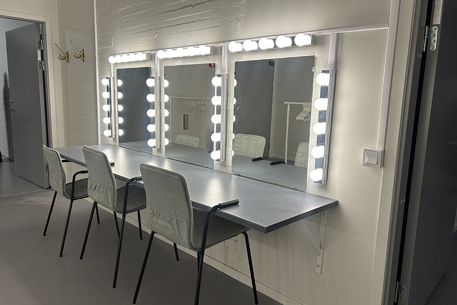 Ett rum med stolar som står framför upplysta speglar. 