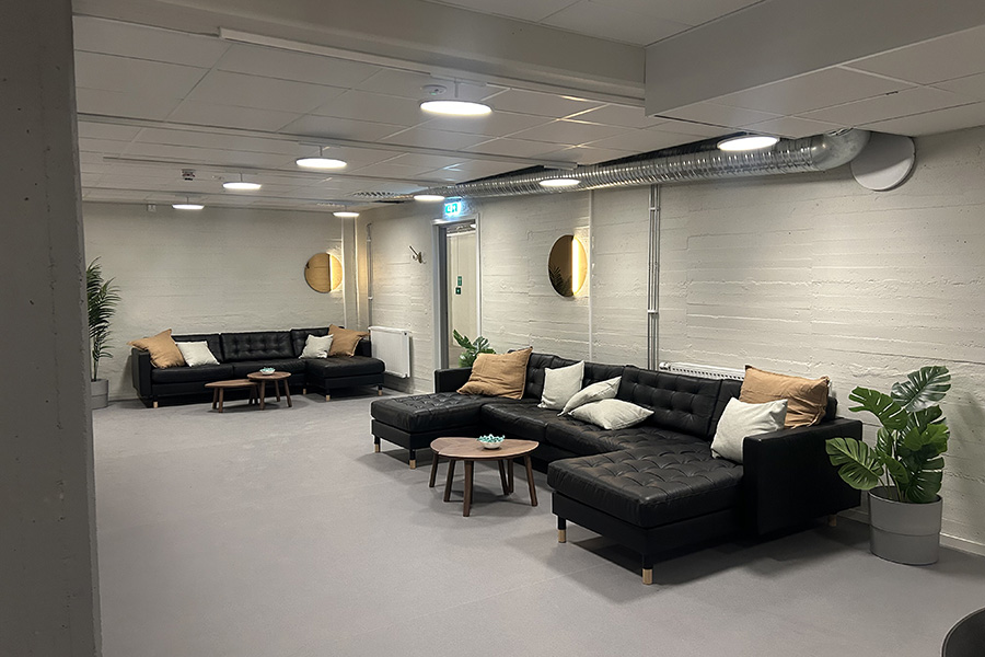 Ett rum med vita väggar. En svart soffa står längst väggen. 