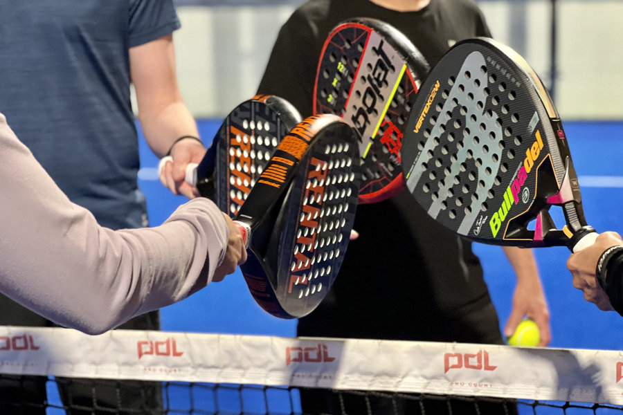 Ett tennisrack i närbild. Framför ligger en tennnisboll.