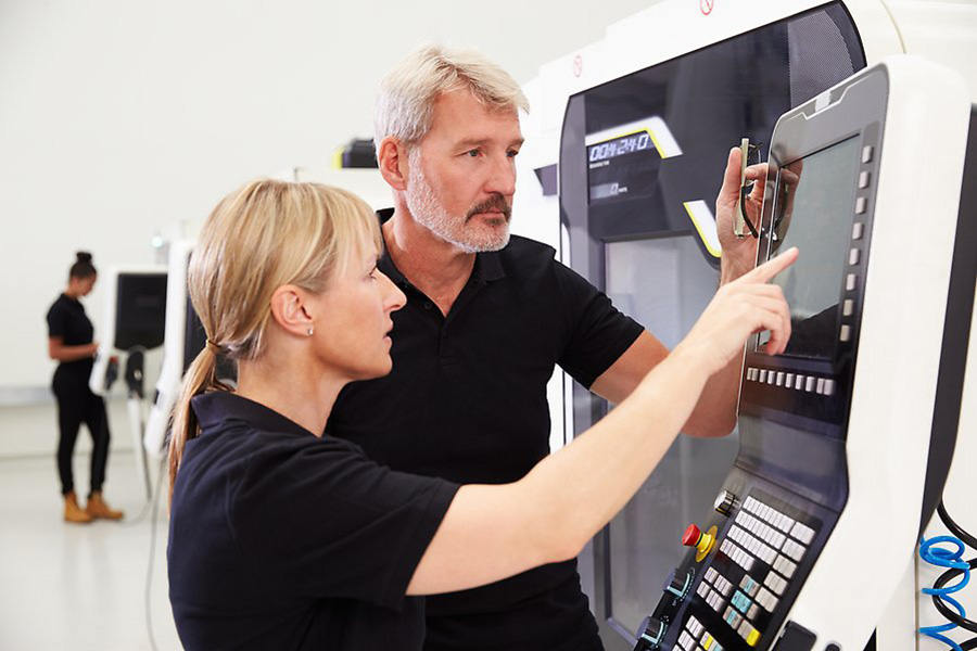 Två medarbetare står vid CAD-maskin