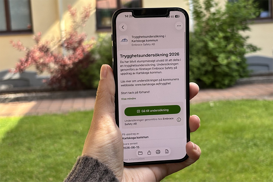 En hand som håller i en telefon med texten " Trygghetsundersökning 2026".