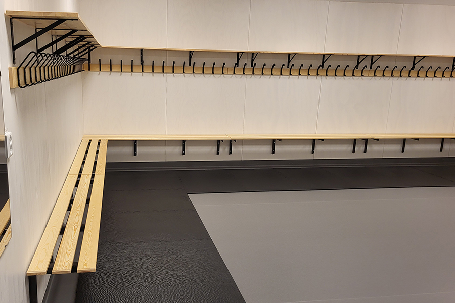 Ett rum med ljusa väggar med träfärgade krokar och bänkar.