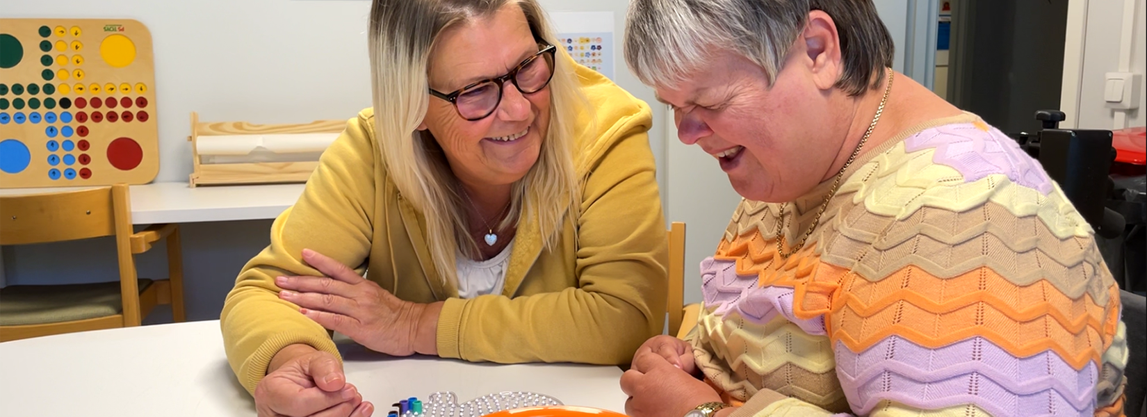 Personlig assistent ler och tittar på sin brukare som också ler