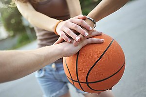 Ett tennisrack i närbild. Framför ligger en tennnisboll. 