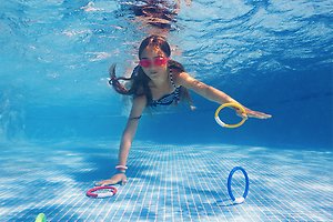 Ett tennisrack i närbild. Framför ligger en tennnisboll. 