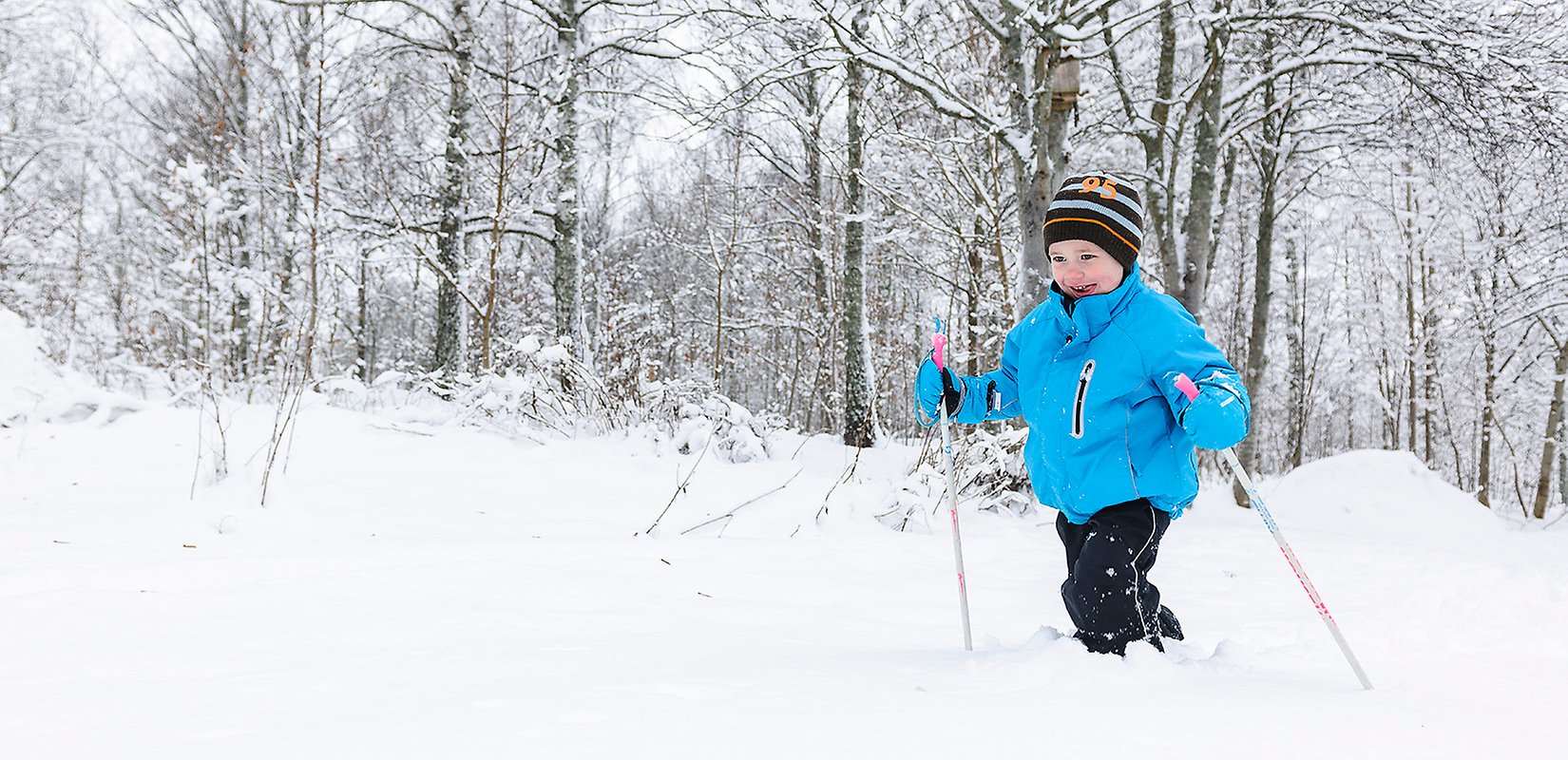 Pojke som åker skidor i snöig terräng.