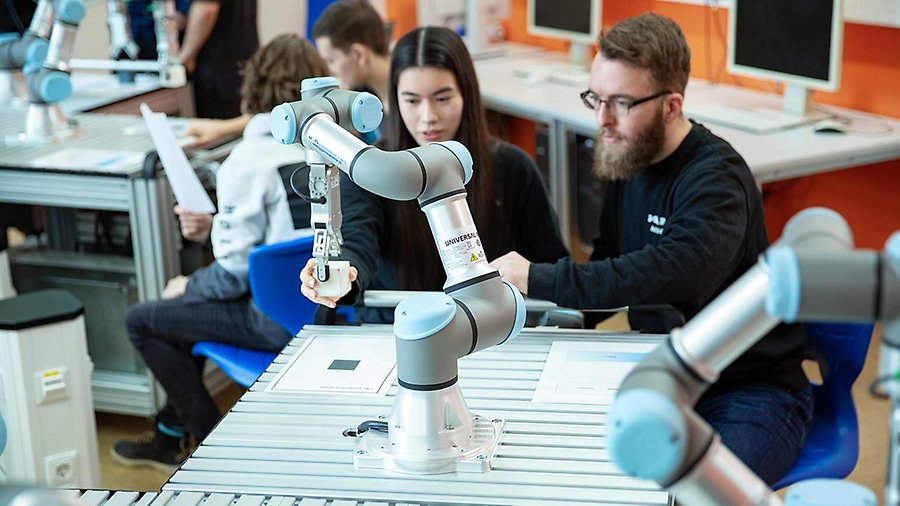 Två personer jobbar med en kollaborativ robot som står på ett bord.