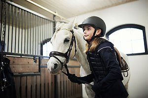 Ett tennisrack i närbild. Framför ligger en tennnisboll. 