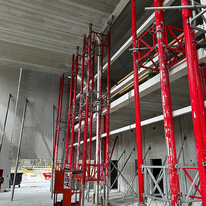 Röda stålramar stöder en betongkonstruktion.