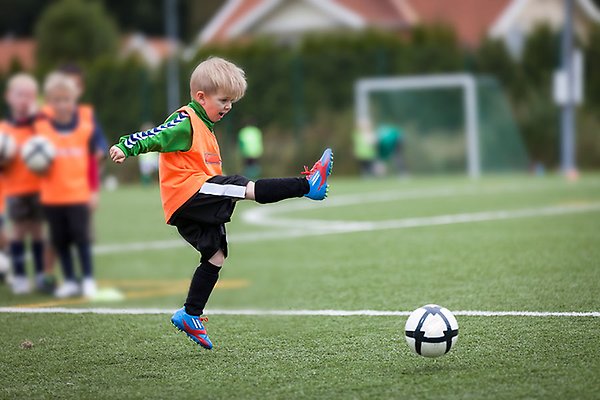 Ett barn som sparkar på en fotboll.